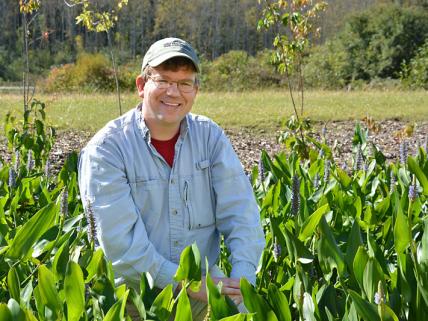 Eric Hellquist kneeling in a green field