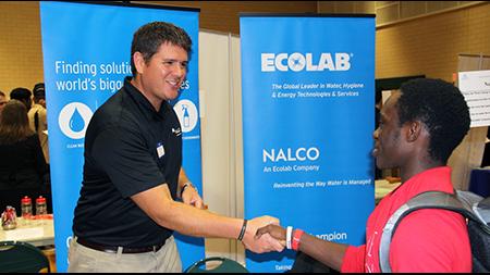 Student shaking hands with an employer at a career fair table