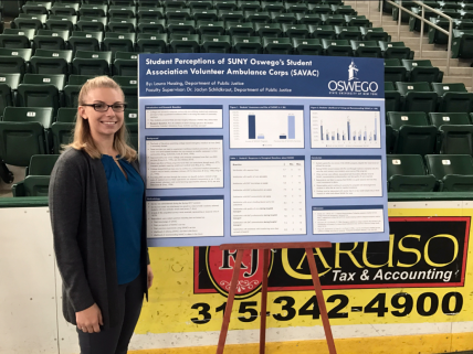 Laura Hussing stands beside research poster in the arena