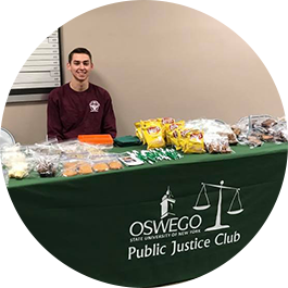 Male student sits at Bake Sale table