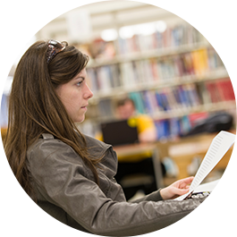 Female student sitting at computer writing paper