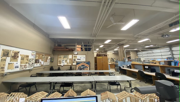 Photo shows the classroom from the podium perspective showing student chairs and PC's 