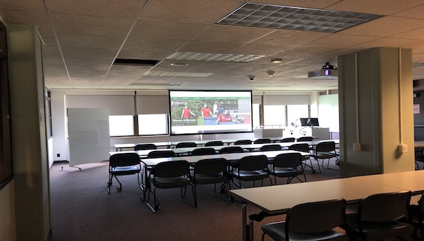 Photo showing the back of the classroom with the projector screen and podium