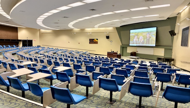 Photo of the back of the room from the side of the classroom. Showing seats, podium, and projector. 