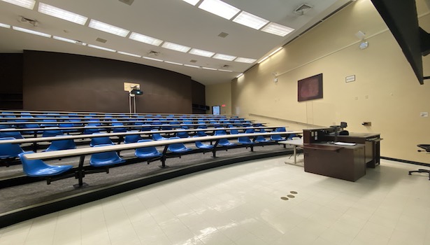 Photo shows the classroom from the front right side including student chairs and projector. 