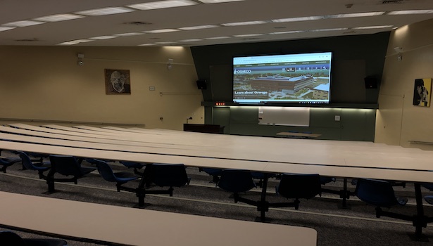 This photo shows the back of the classroom with all of the seats and the large projector screen. 