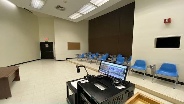 Photo of the classroom from the teacher standpoint. Showing off the podium equiptment and student chairs. 