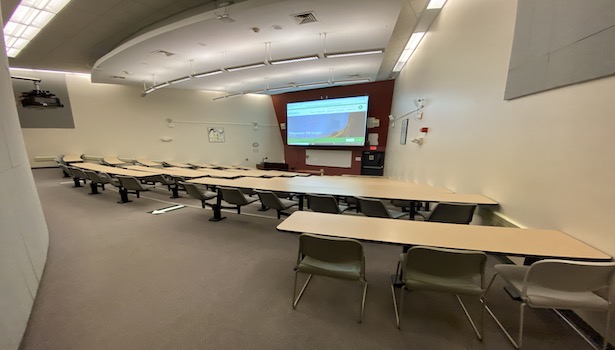 Photo shows the front of the class from the back right side. Showing student MAC's and the projector screen. 