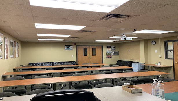 Photo shows the back of the room from the podium perspective. Including student seating and the front of the podium. 