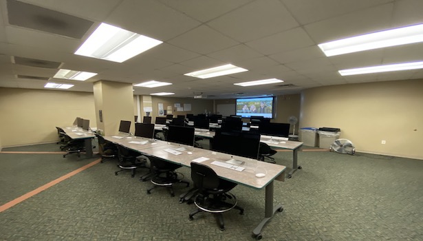 Photo of the back of the classroom on the right side. Including student MAC's, and the projector screen/podium. 