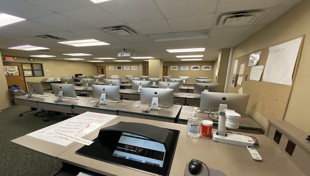 Photo of the classroom from the podium showing the computer screen and the student MAC's. 