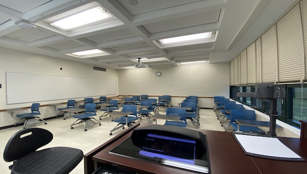 Photo shows the back of the classroom from the podium perspective. Including the Doc cam, PC and student chairs. 