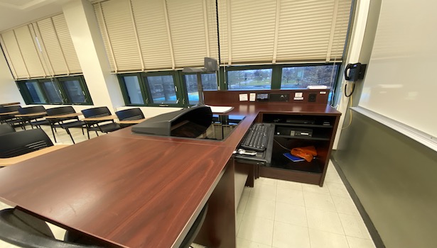 Photo shows the podium in the classroom including the PC, touch panel, document camera and phone. 