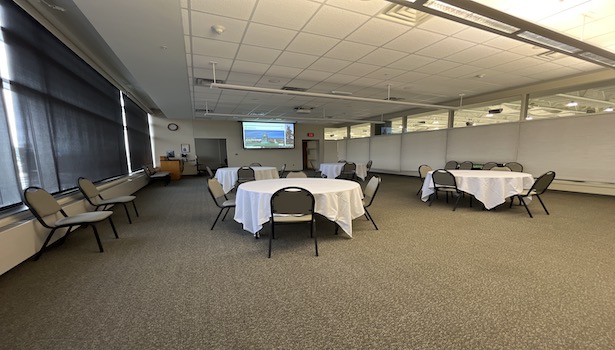 Photo shows the back of the room from the front left side. Including chairs, tables and the south projector. 