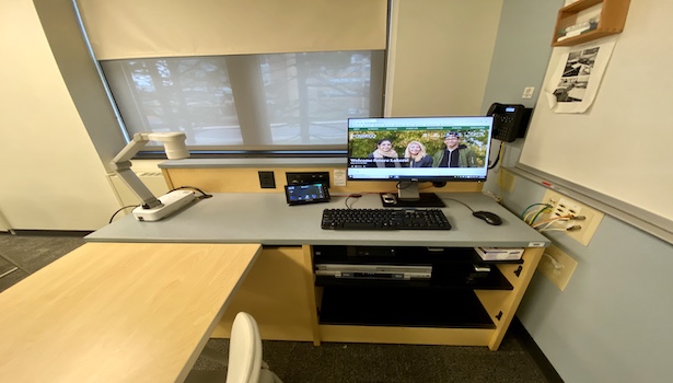 Photo shows the podium in the classroom including the PC, touch panel, document camera and phone. 