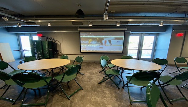 Photo shows the north projector screen with chairs and tables. 