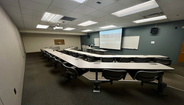 photo from the back of the room to show the entire classroom. including projector screen and student chairs. 