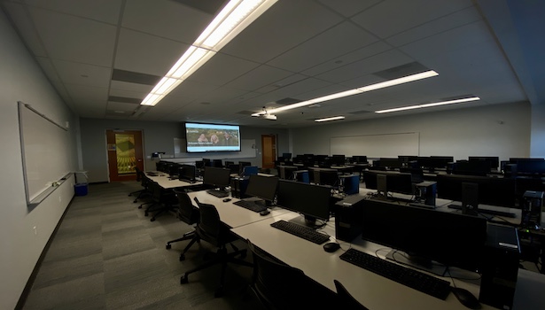This is a photo of the classroom from the back left corner. Including student PC's and the professor's podium. 
