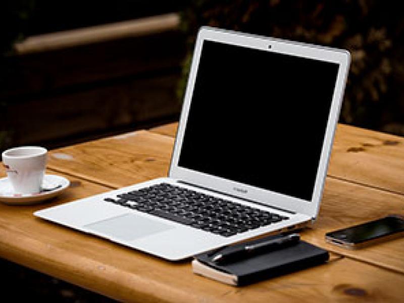 laptop on desk with coffee cup and organizer
