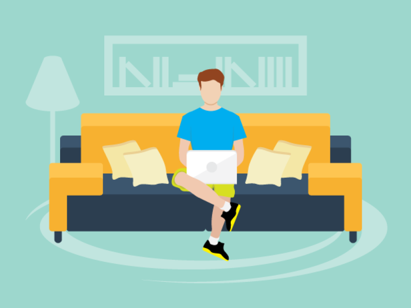 Person siting on the couch at home working on a laptop.