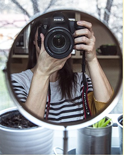 Photo of a person taking a photograph of themself in a mirror