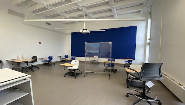 Photo shows the classroom from podium perspective. Showing student chairs and projector. 