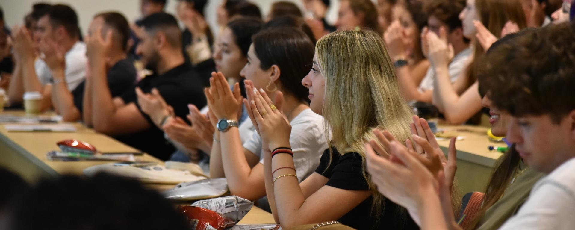 Image showing a group of international students seated in rows, engaging in a round of applause during International students orientation.