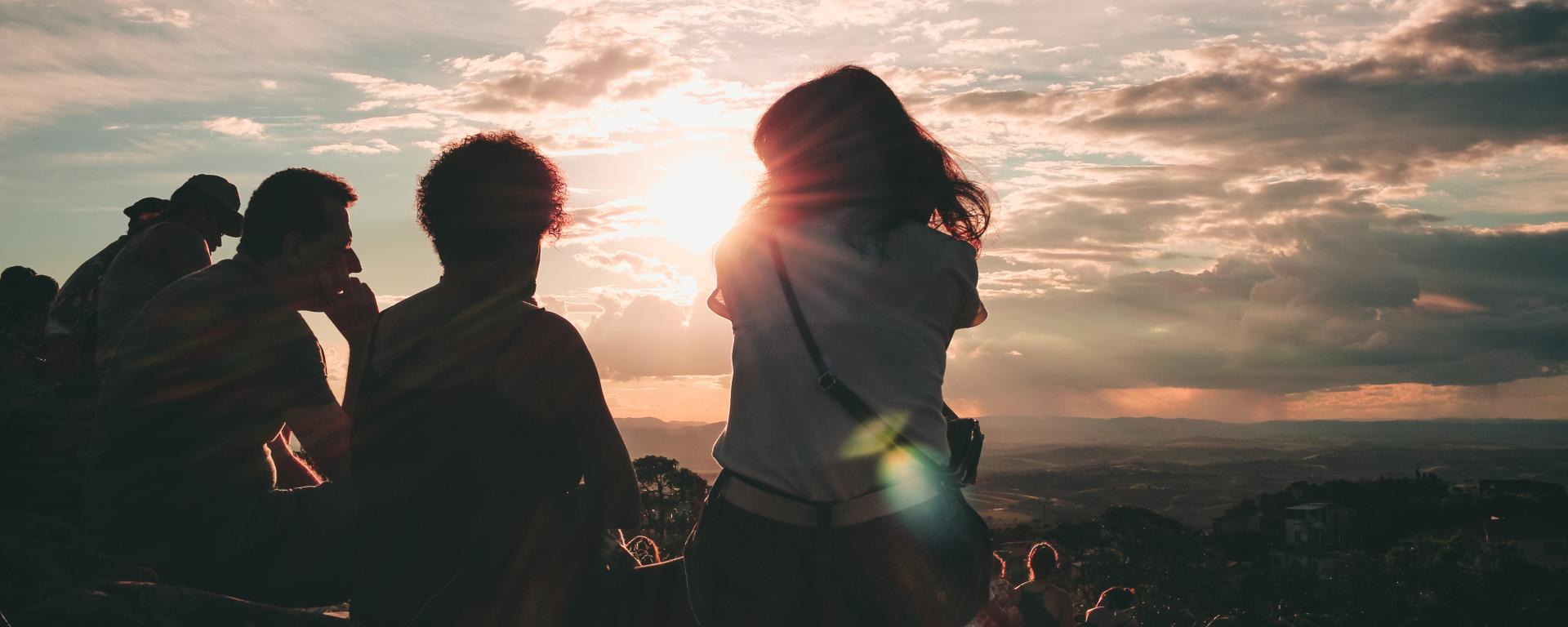 Students traveling together, looking out at the sunset over mountains.