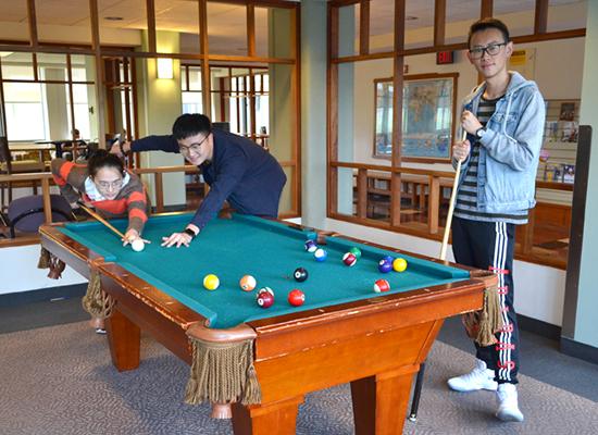 Student play pool in a Hart Hall lounge.