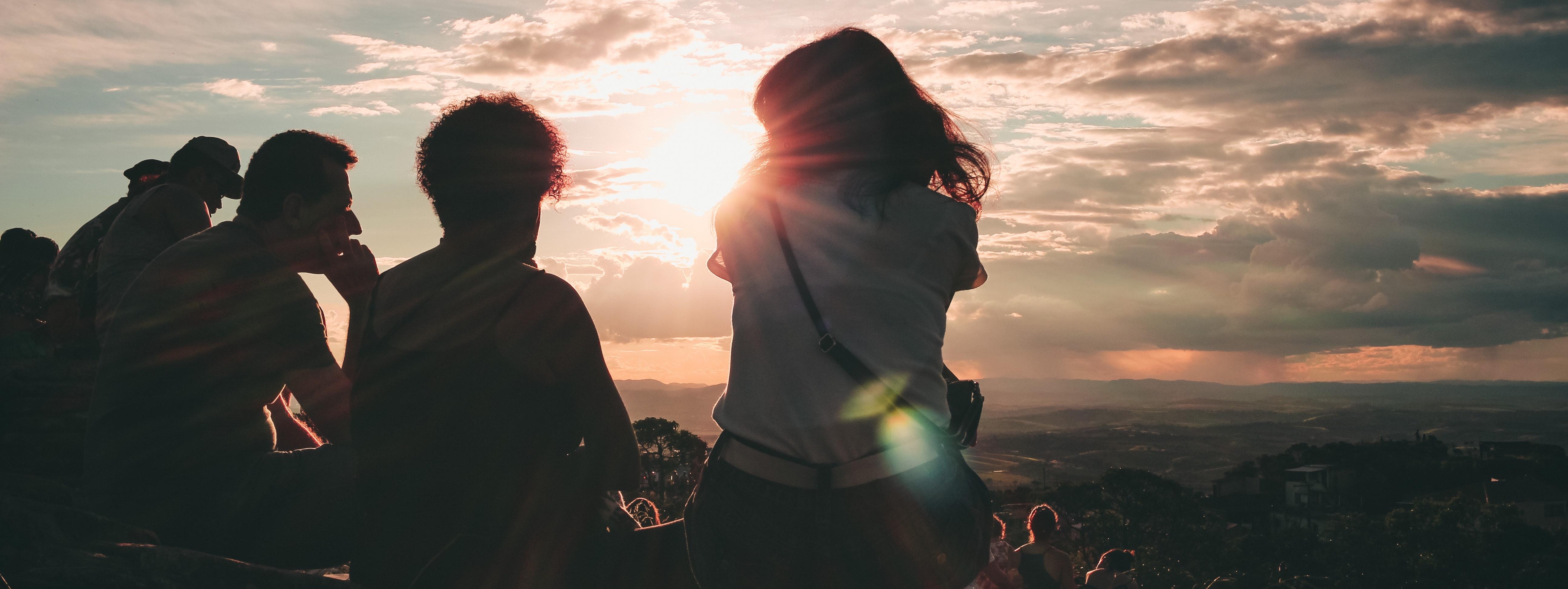 Students traveling together, looking out at the sunset over mountains.