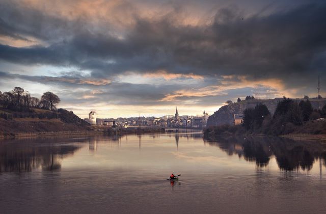 Someone kayaking in the river with Ireland city in the background