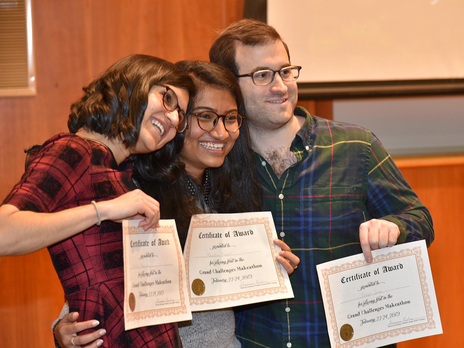 Three students with certificates after their app proposal won Grand Challenges Makeathon