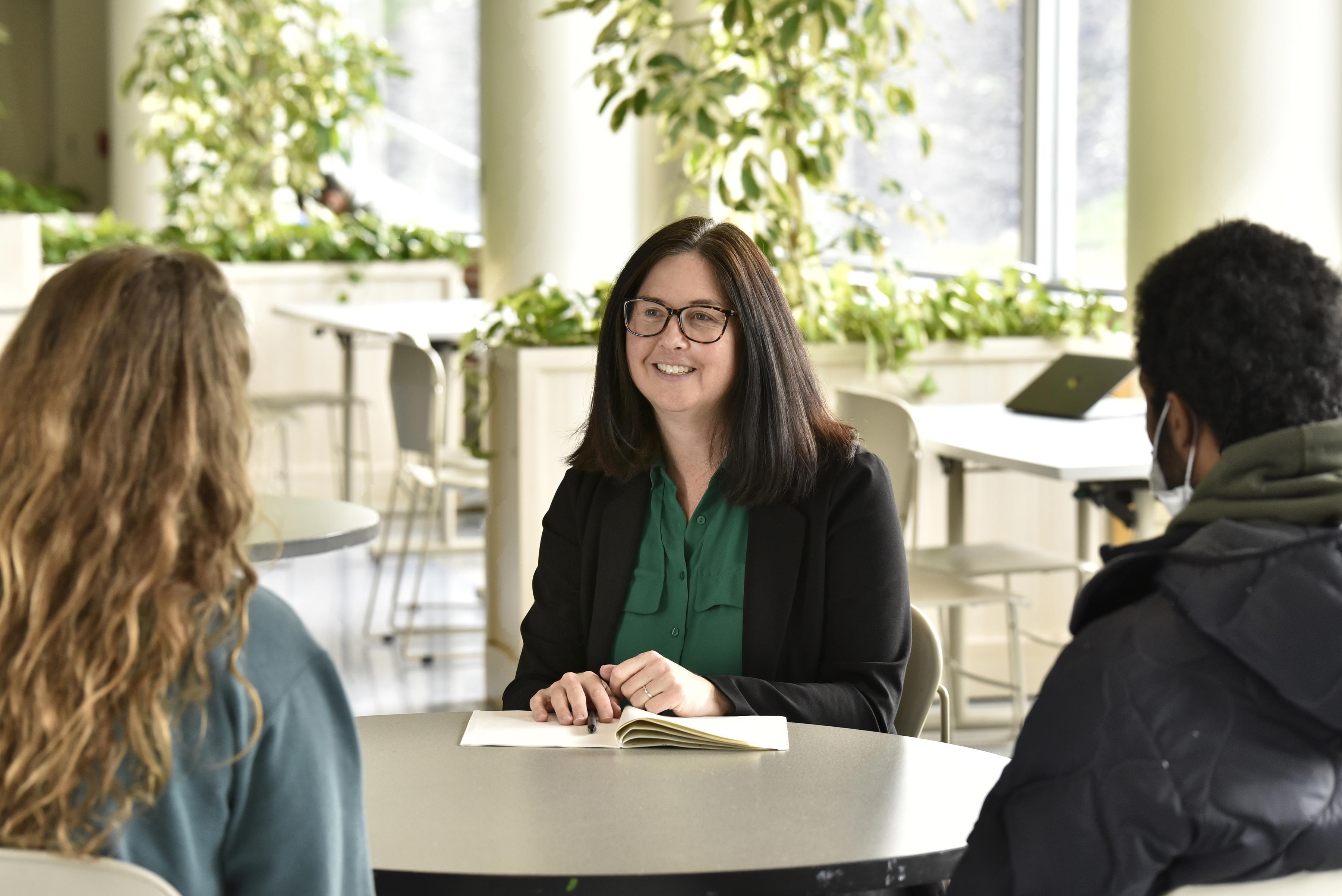 Christy Huynh talking with students Alyssa Frantz, a junior, and Aron Rezene, a senior