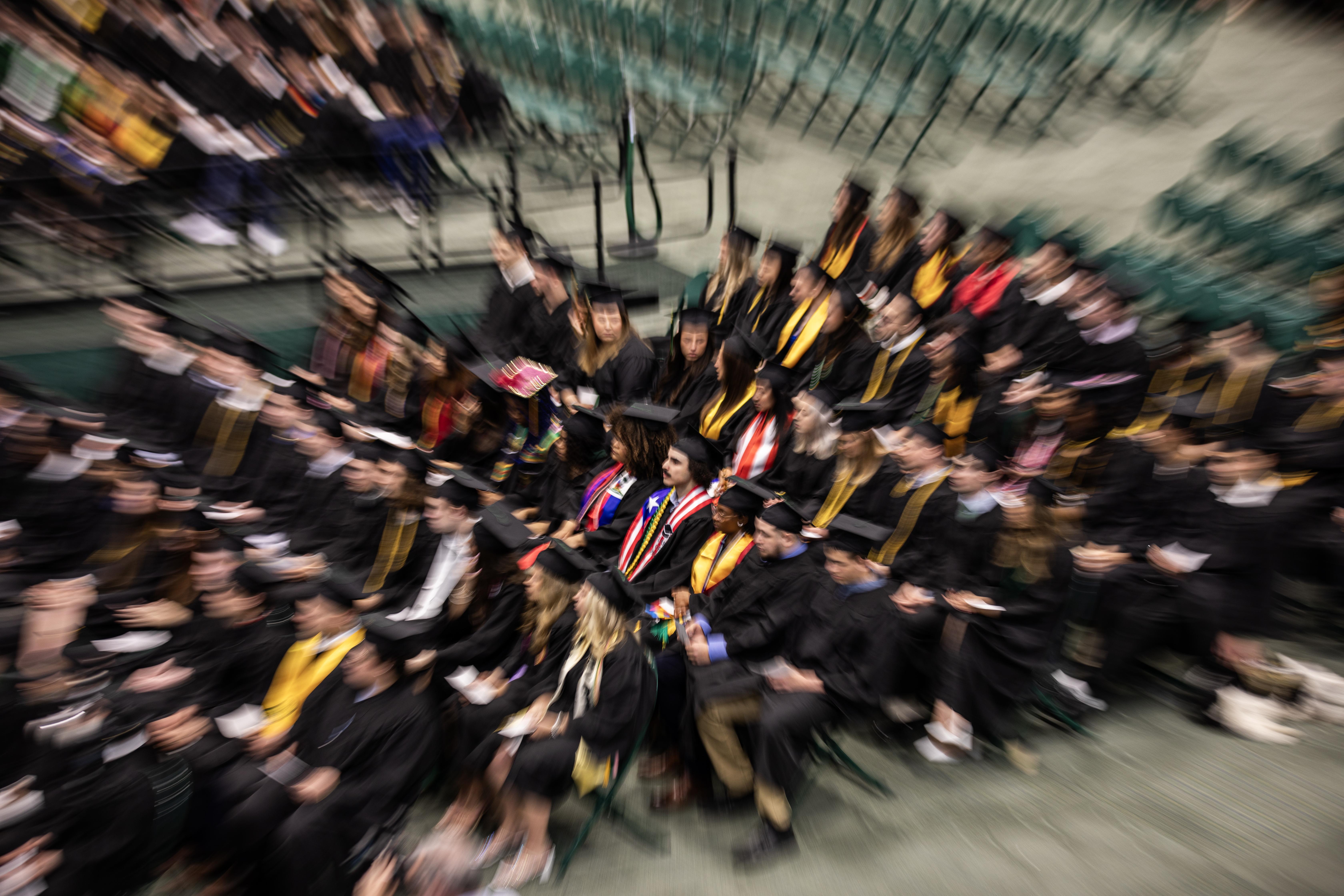 commencement photo of students sitting in their chairs that is half blurred 