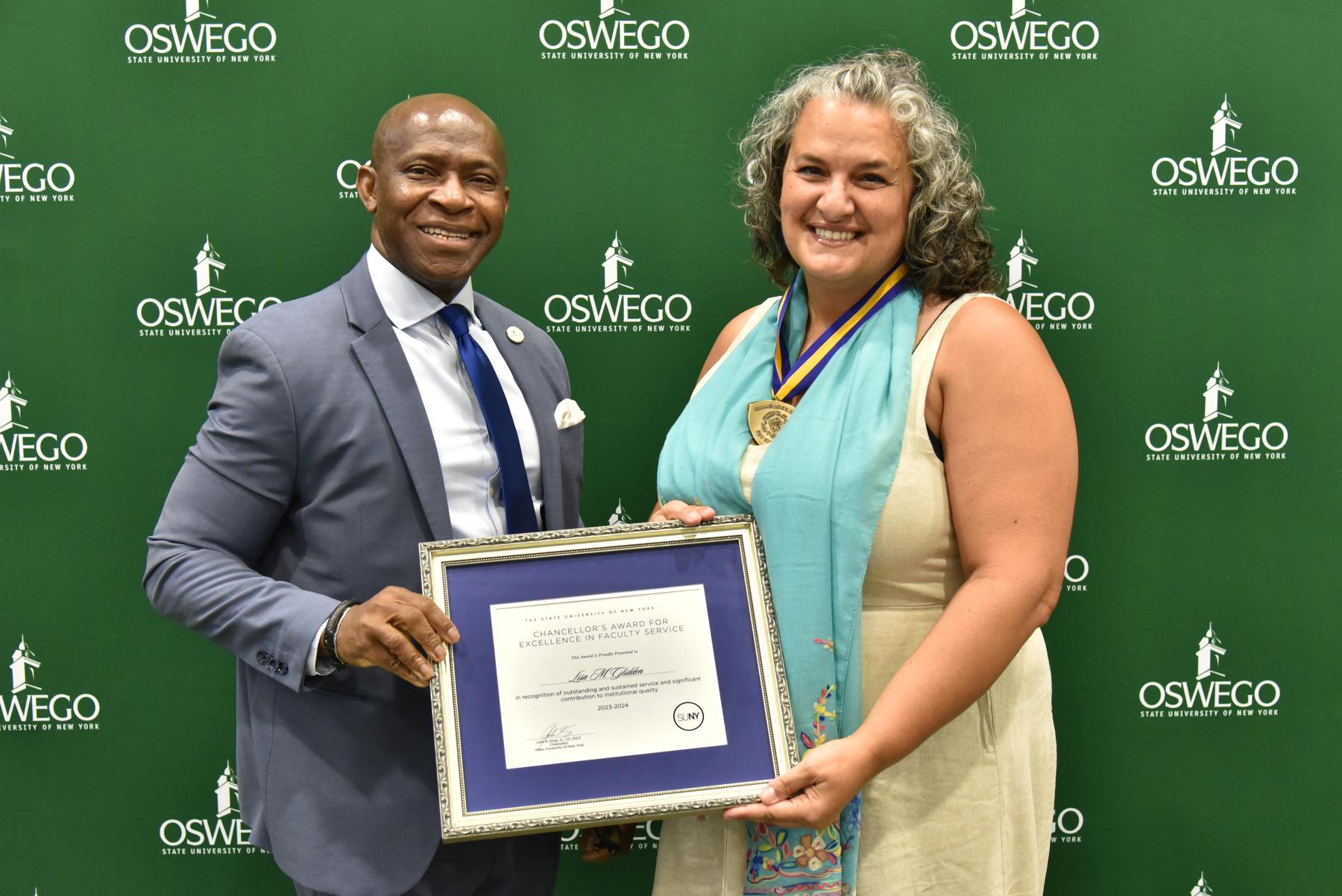 Politics professor Lisa Glidden receives her Chancellor's Award for Excellence in Faculty Service and congratulations from President Peter O. Nwosu at SUNY Oswego's Opening Breakfast on Aug. 20. 