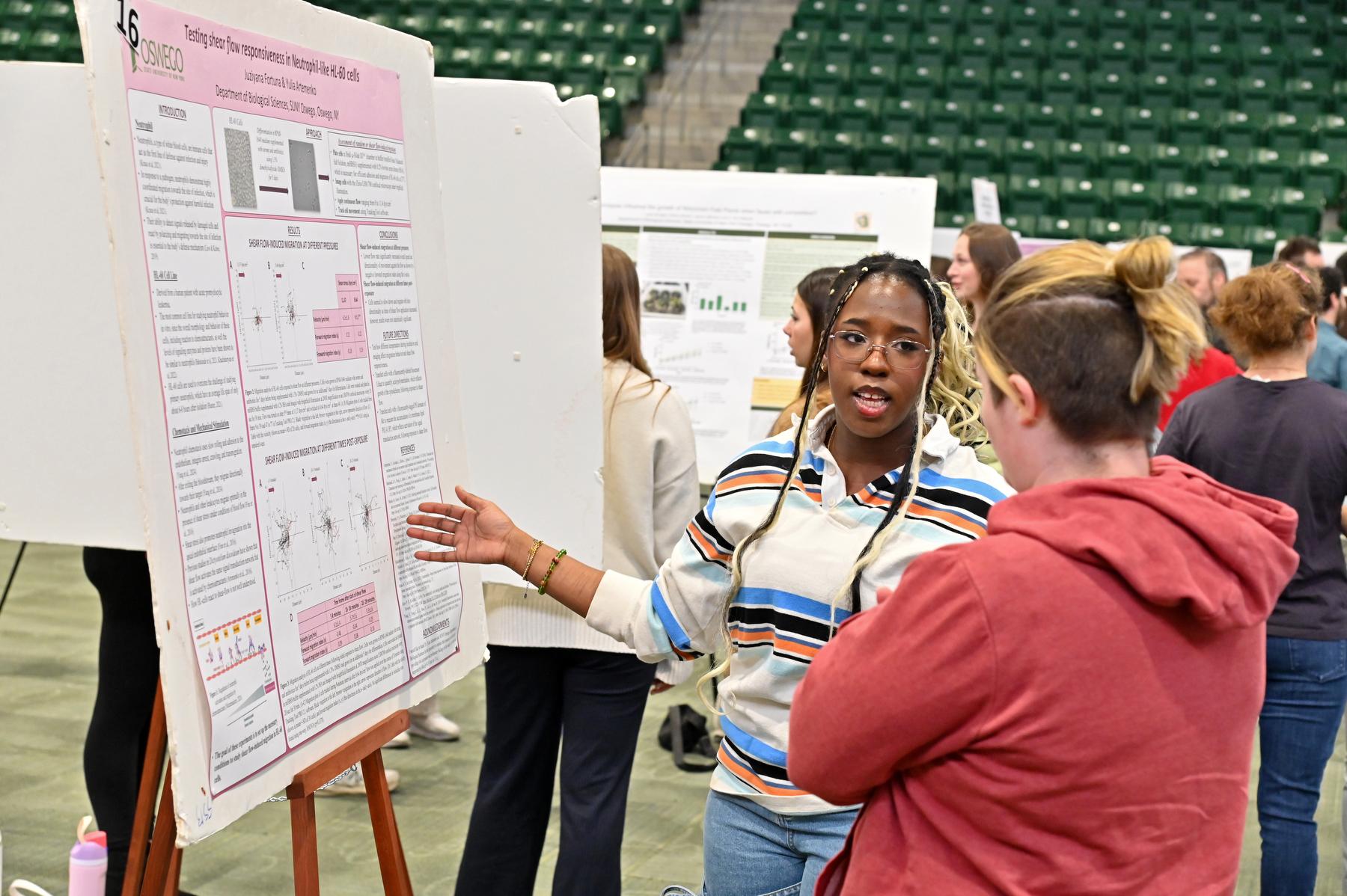 Biological sciences student Juziyana Fortuna talks about her "Testing shear flow responsiveness in Neutrophil-like HL-60 cells" during the April 23 Quest poster presentation session in the Deborah F. Stanley Arena and Convocation Hall.