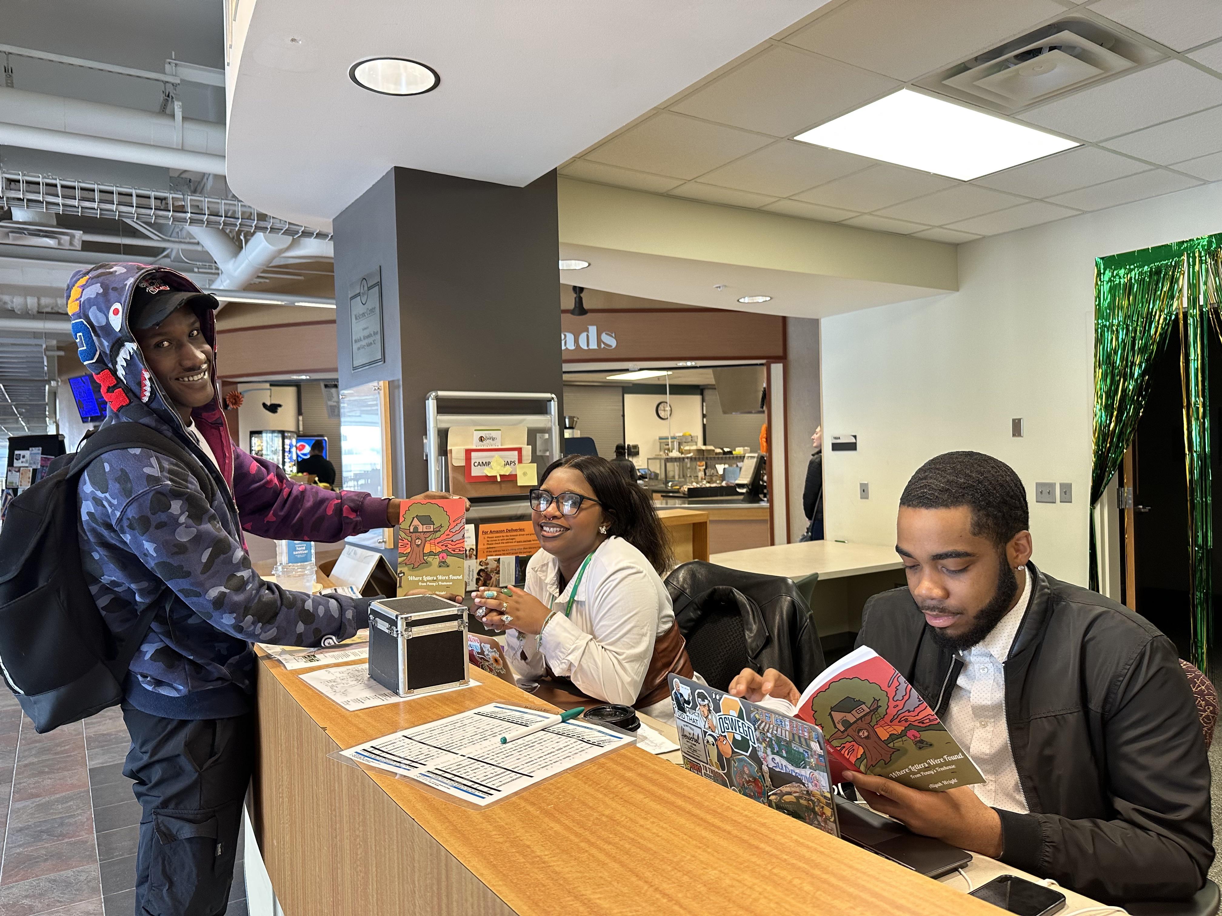 Aliyah Wright and two co-workers look over her book of poetry