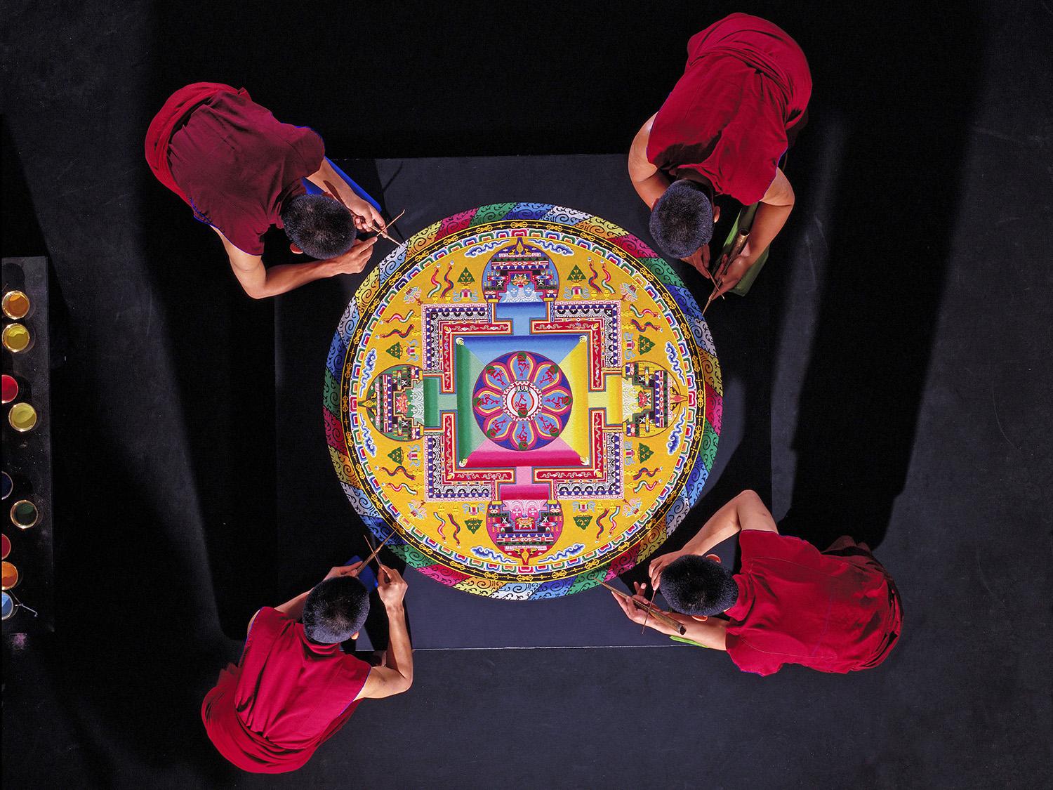 Tibetan monks of the Drepung Loseling Monastery work on sand art painting