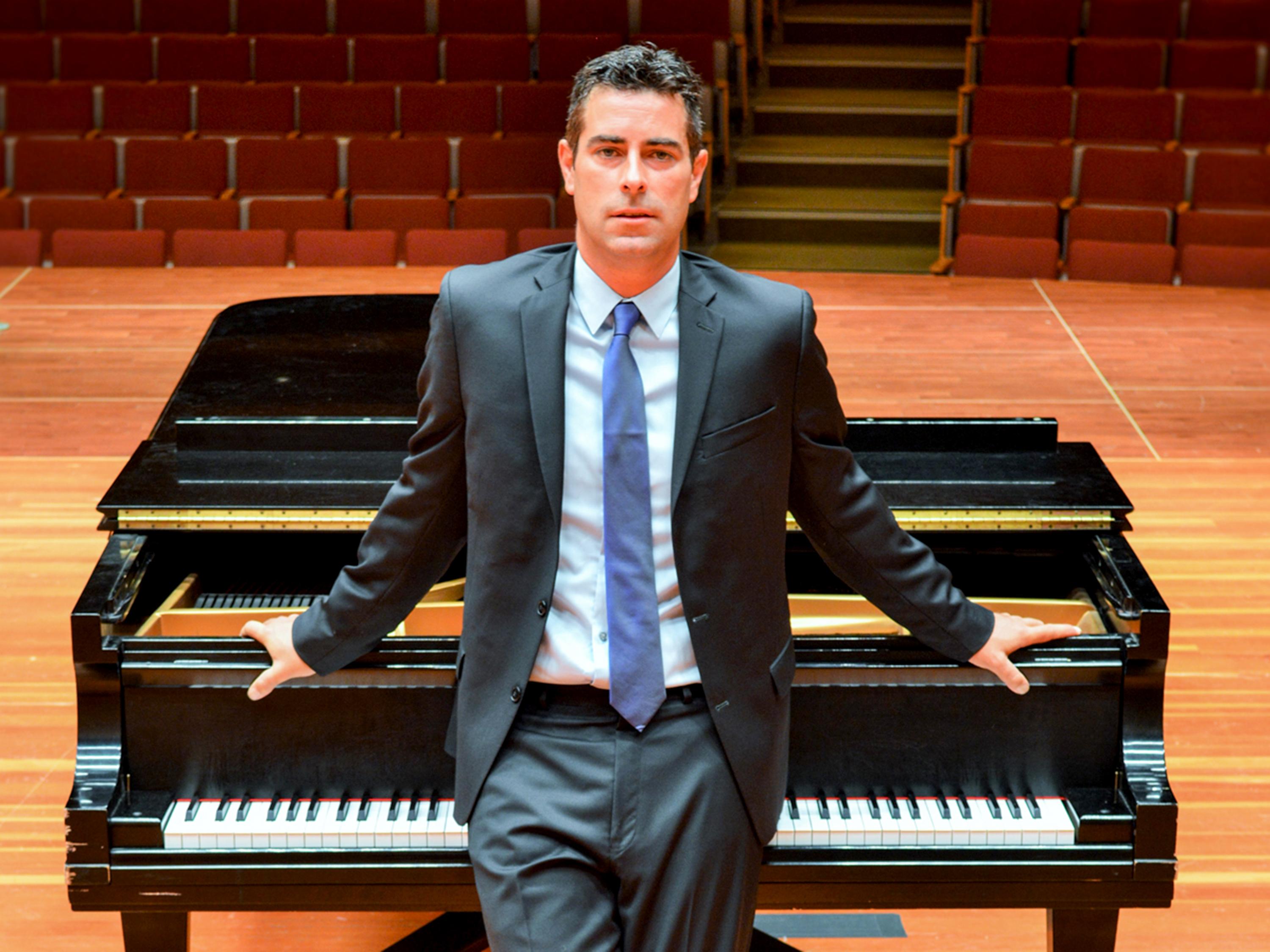 Robert Auler stands at a piano