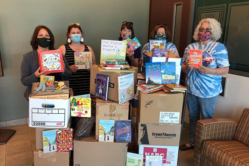 College participants and Oswego Bookmobile volunteers show off some of the hundreds of books donated to the local cause