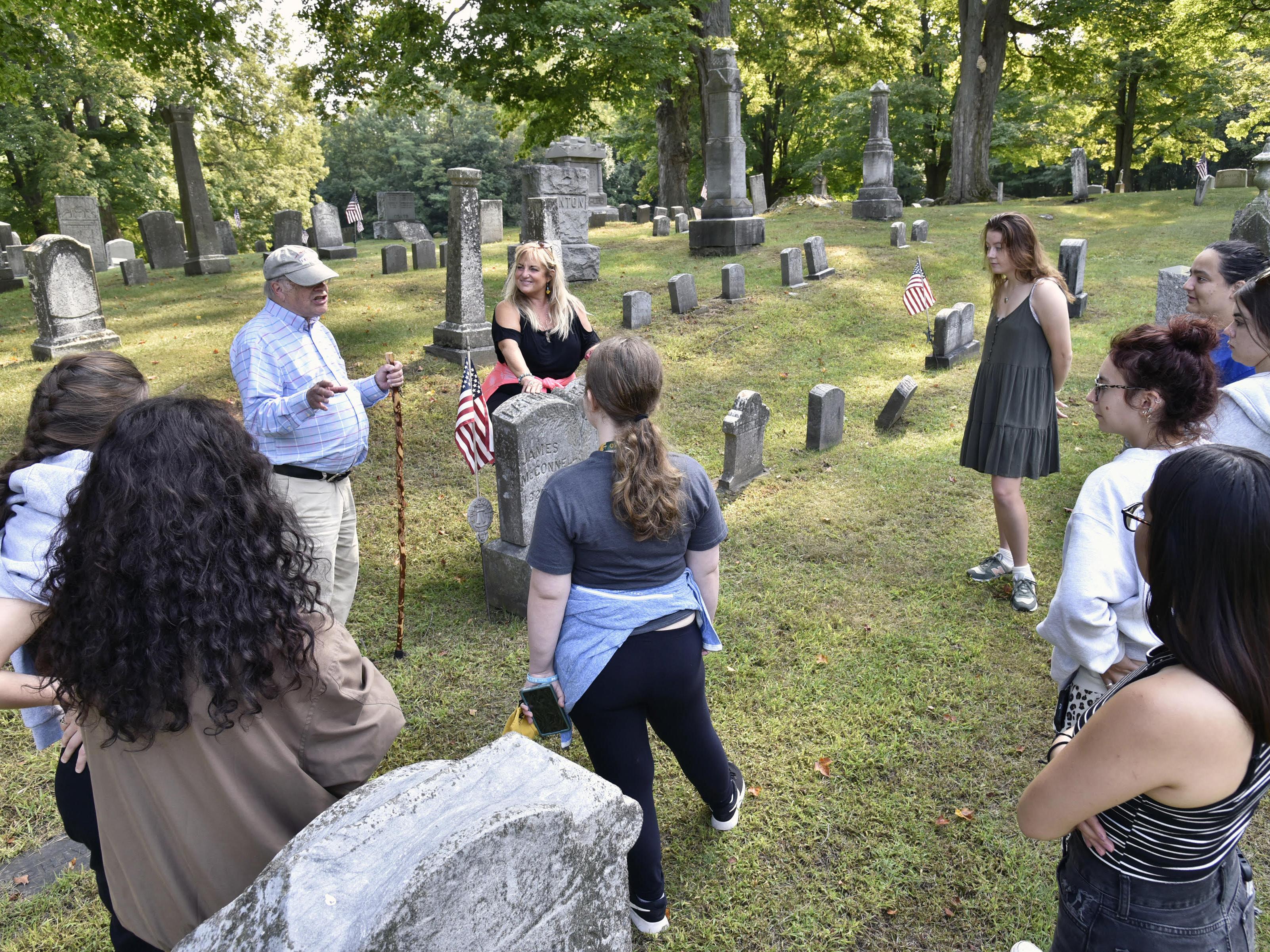 Oswego Town Historian (and 1966 SUNY Oswego alumnus) George DeMass speaks with theatre faculty member Jonel Langenfeld (center) and students from the college's storytelling class as they prepare for a family-friendly cemetery storytelling tour Oct. 29