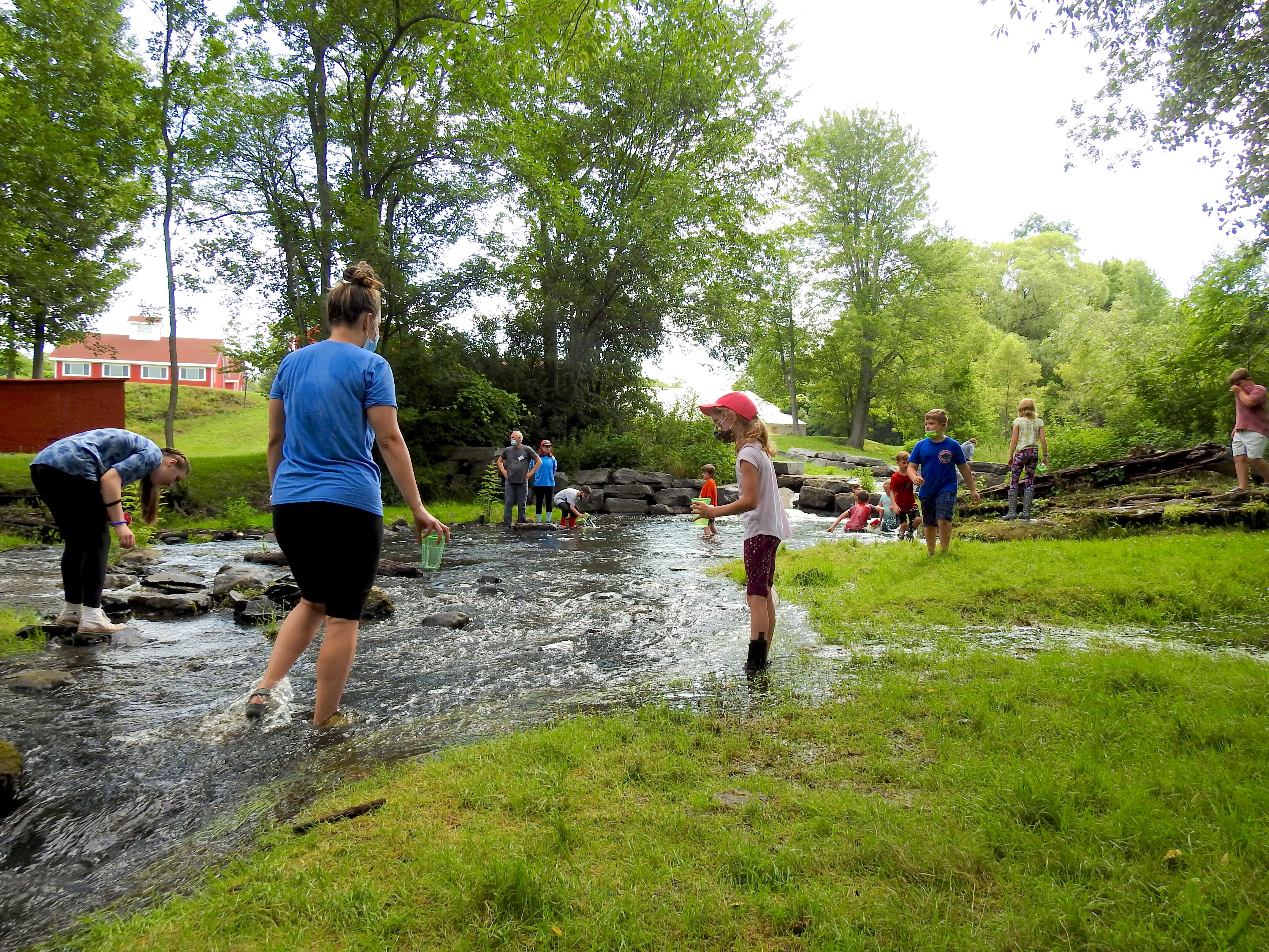 An instructor works with youngsters in a creek during a previous Explore Nature summer session