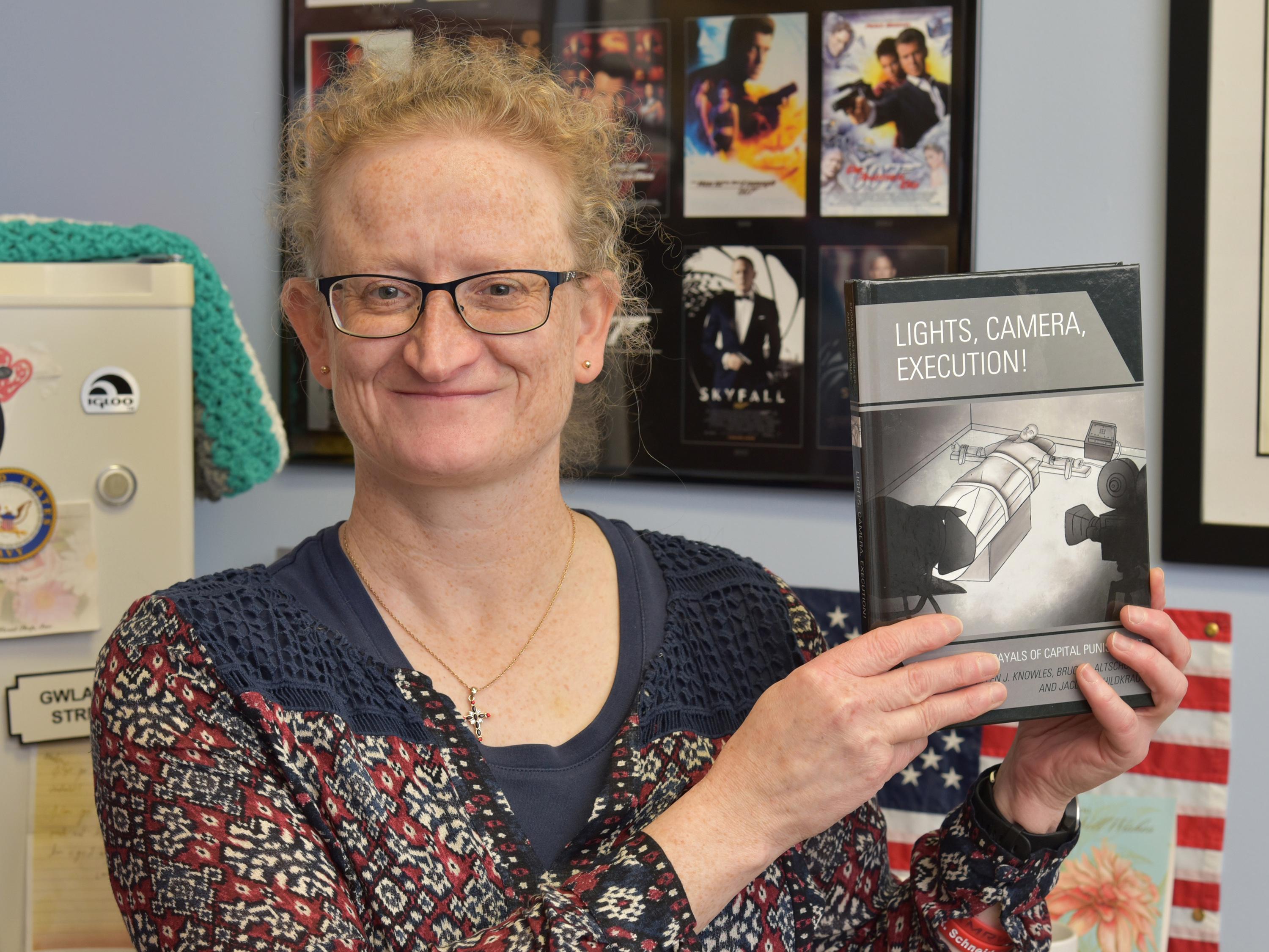 Helen Knowles with book Lights, Camera, Execution, a collaboration of three faculty members