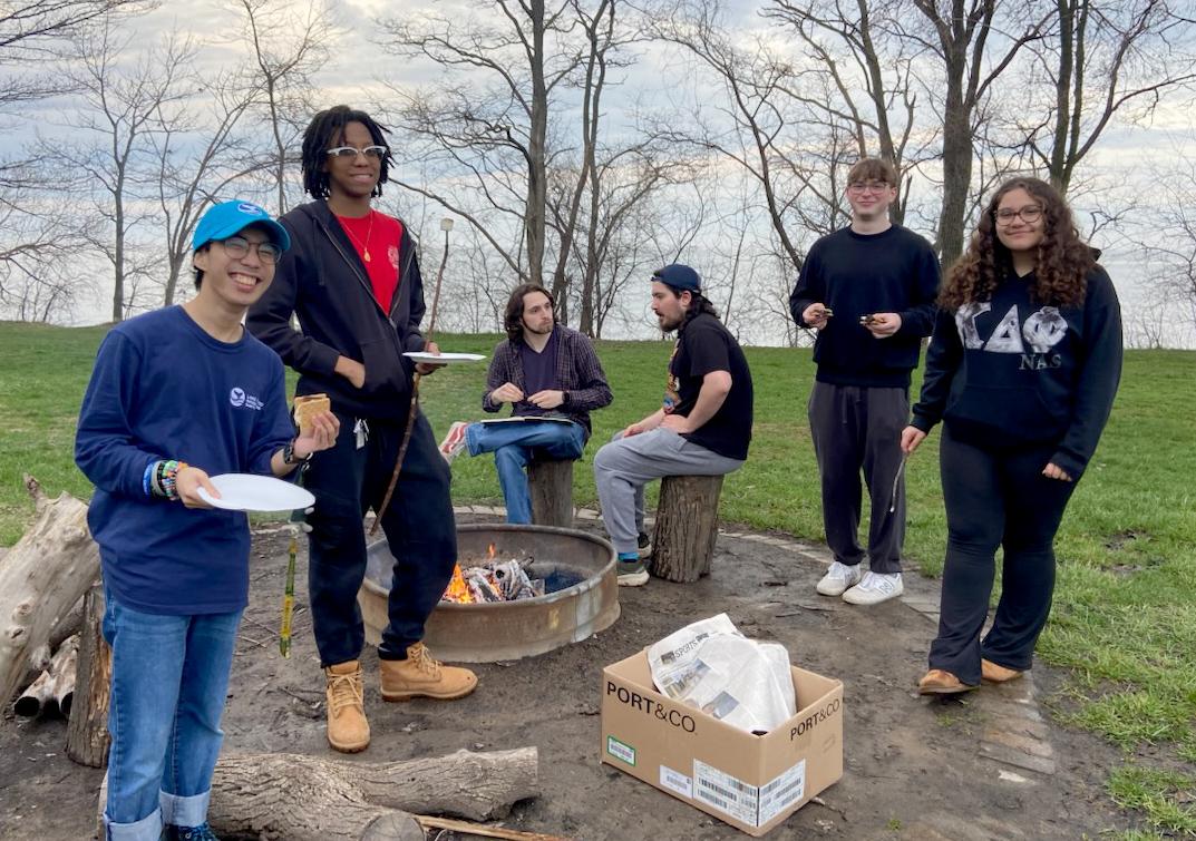 Great Lakes Institute interns and student volunteers with Shining Waters lakeshore cleanup pause during a post-pickup bonfire