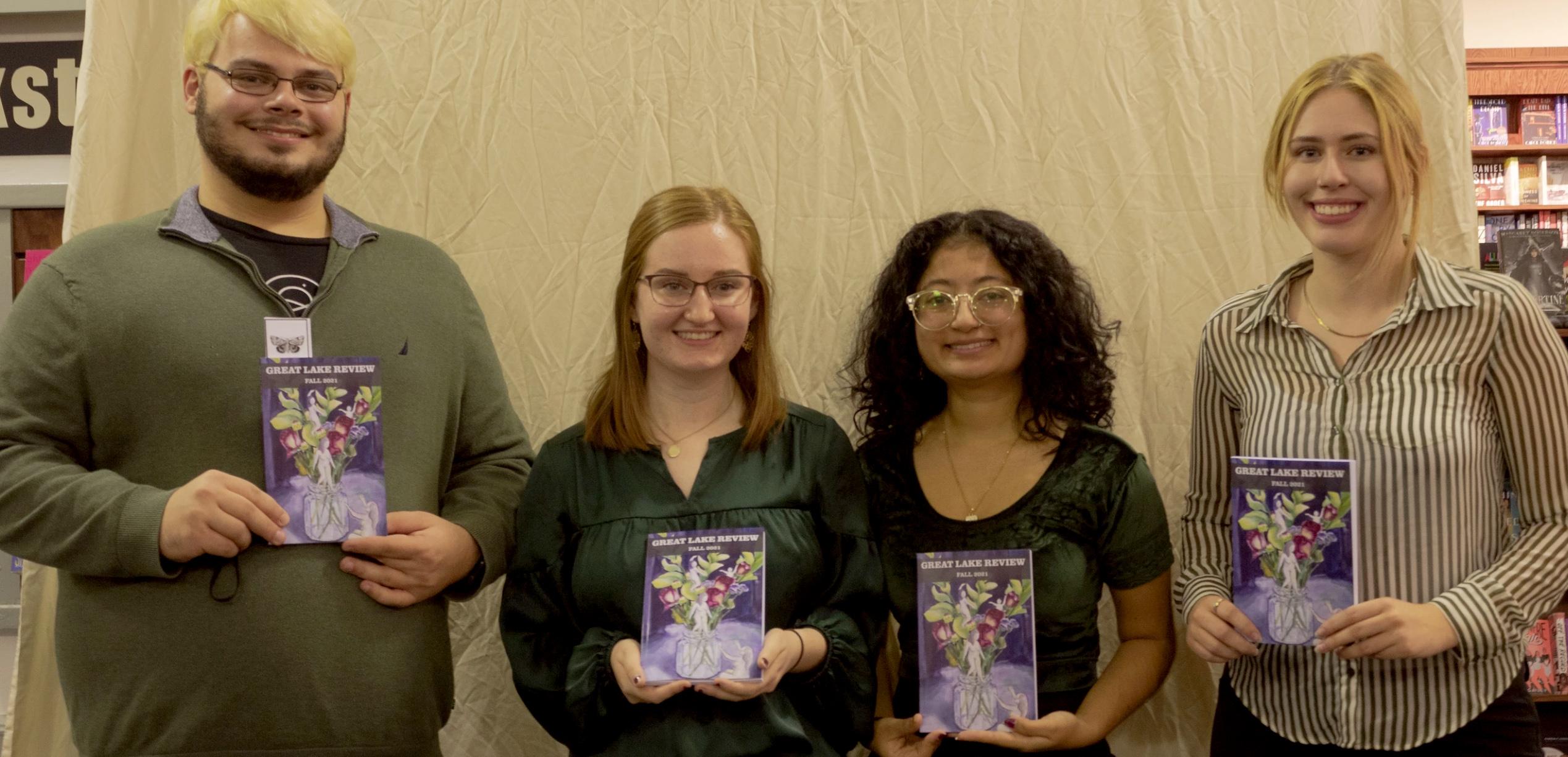 Students with Great Lake Review hold a previous edition of the magazine during a release party at the River's End Bookstore