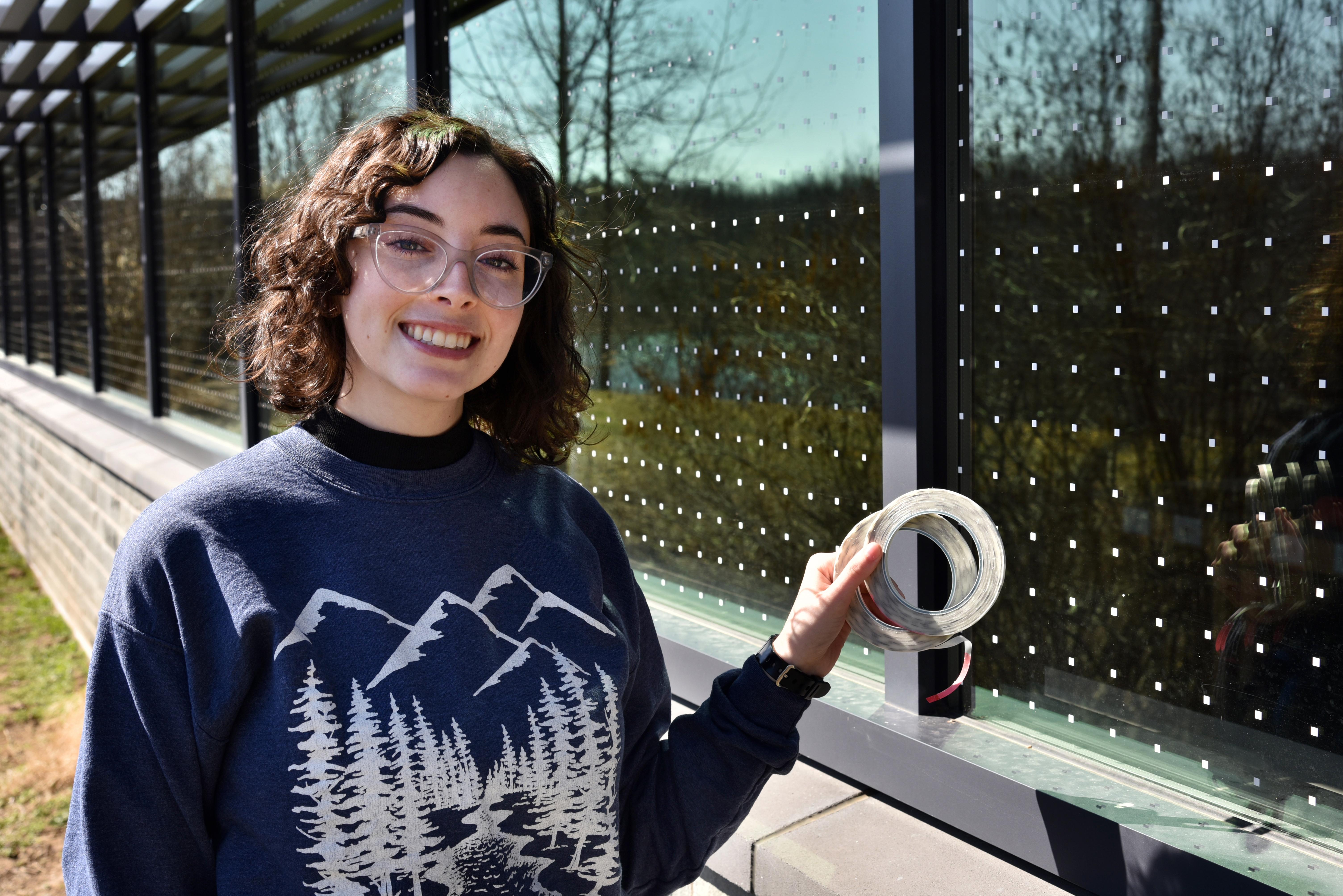 Senior zoology major Brooke Goodman shows off some of the window stickers at Rice Creek that serve as deterrents for birds