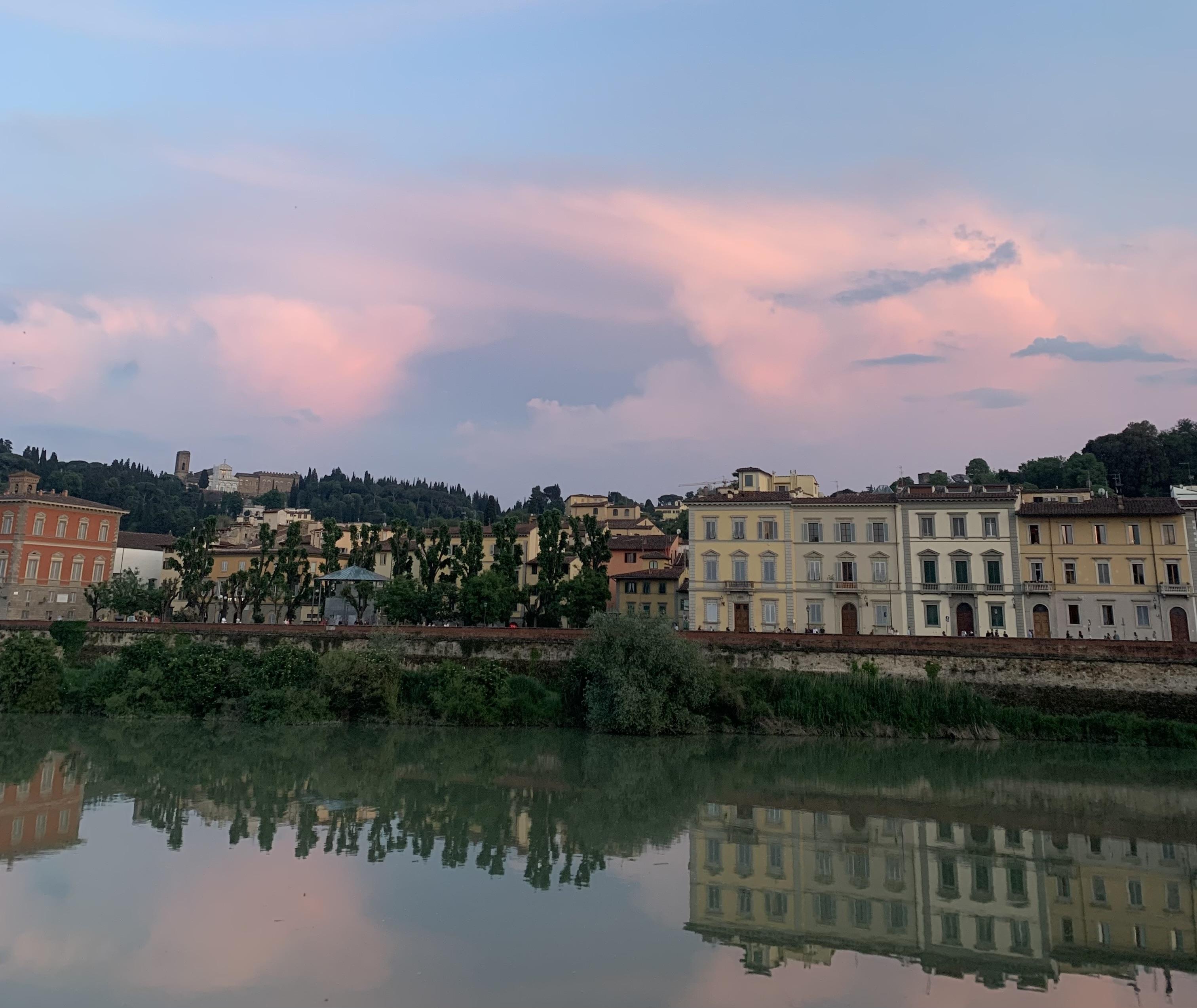 A beautiful pink, purple and blue sunset in Florence, Italy. The buildings reflect off of the clear blue water.