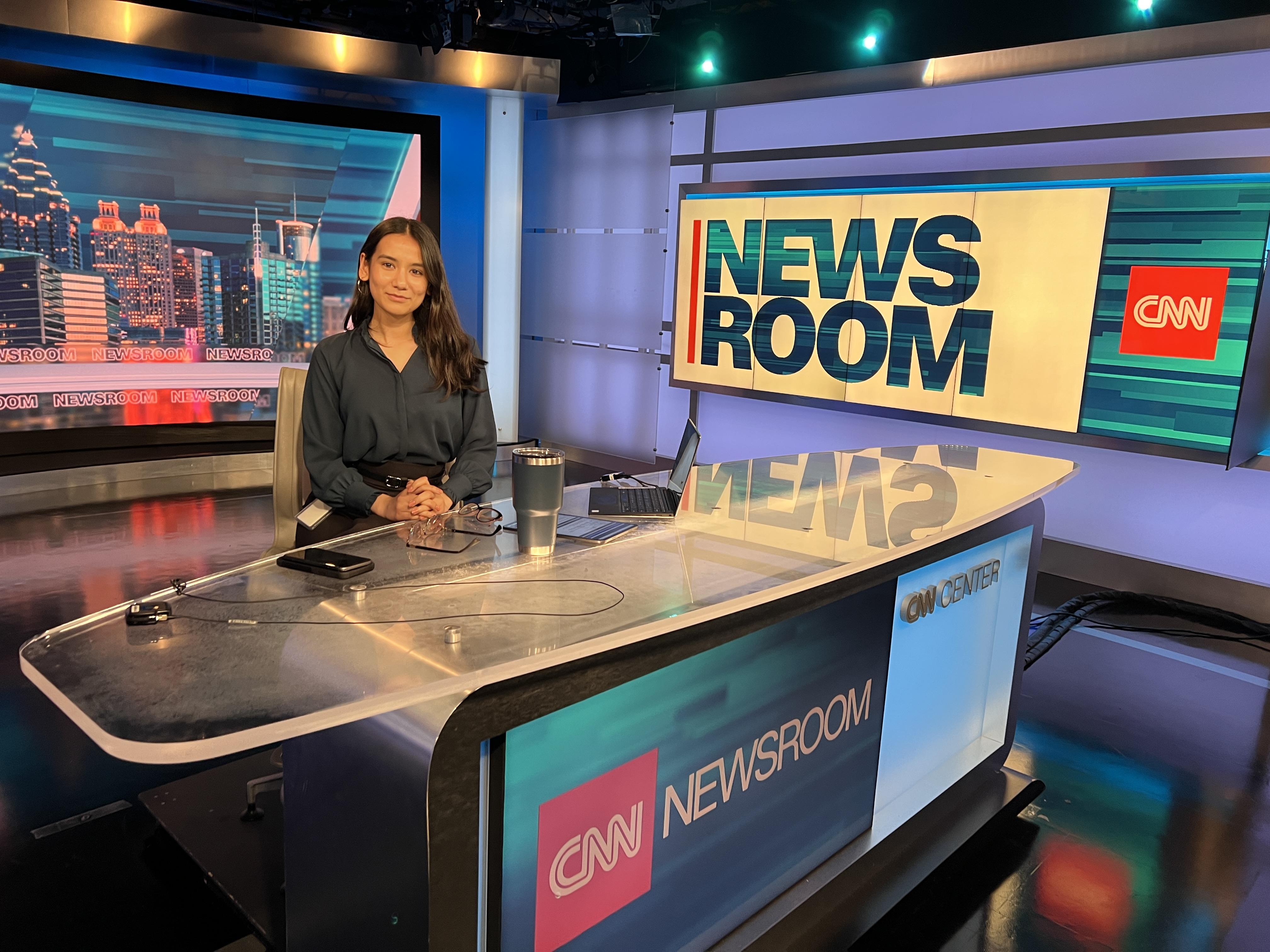 SUNY Oswego student Clarissa Karki sitting at the CNN newsroom anchor desk.