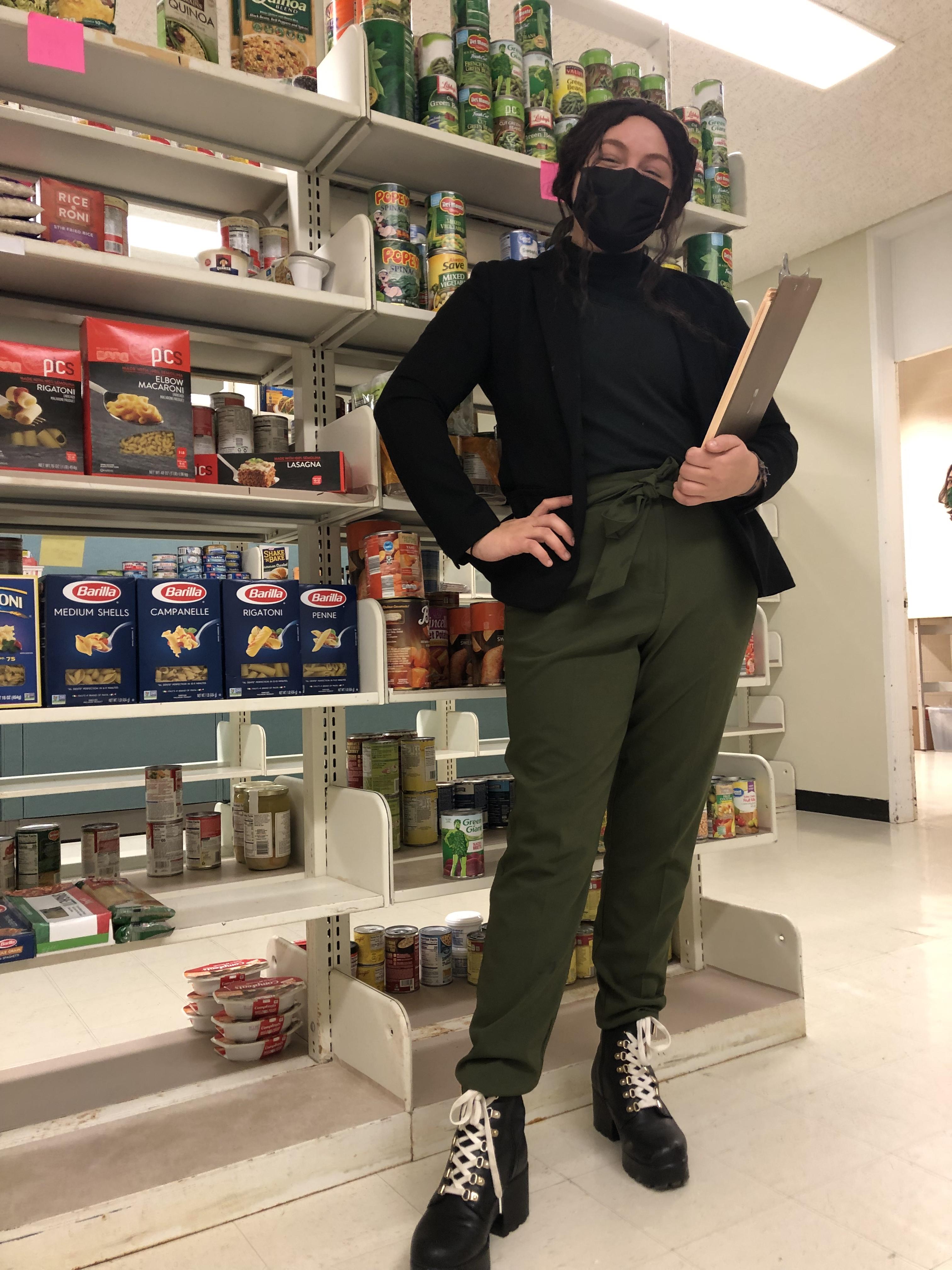 Senior Helena Buttons, SHOP Coordinator, standing in front of shelves with food at SHOP