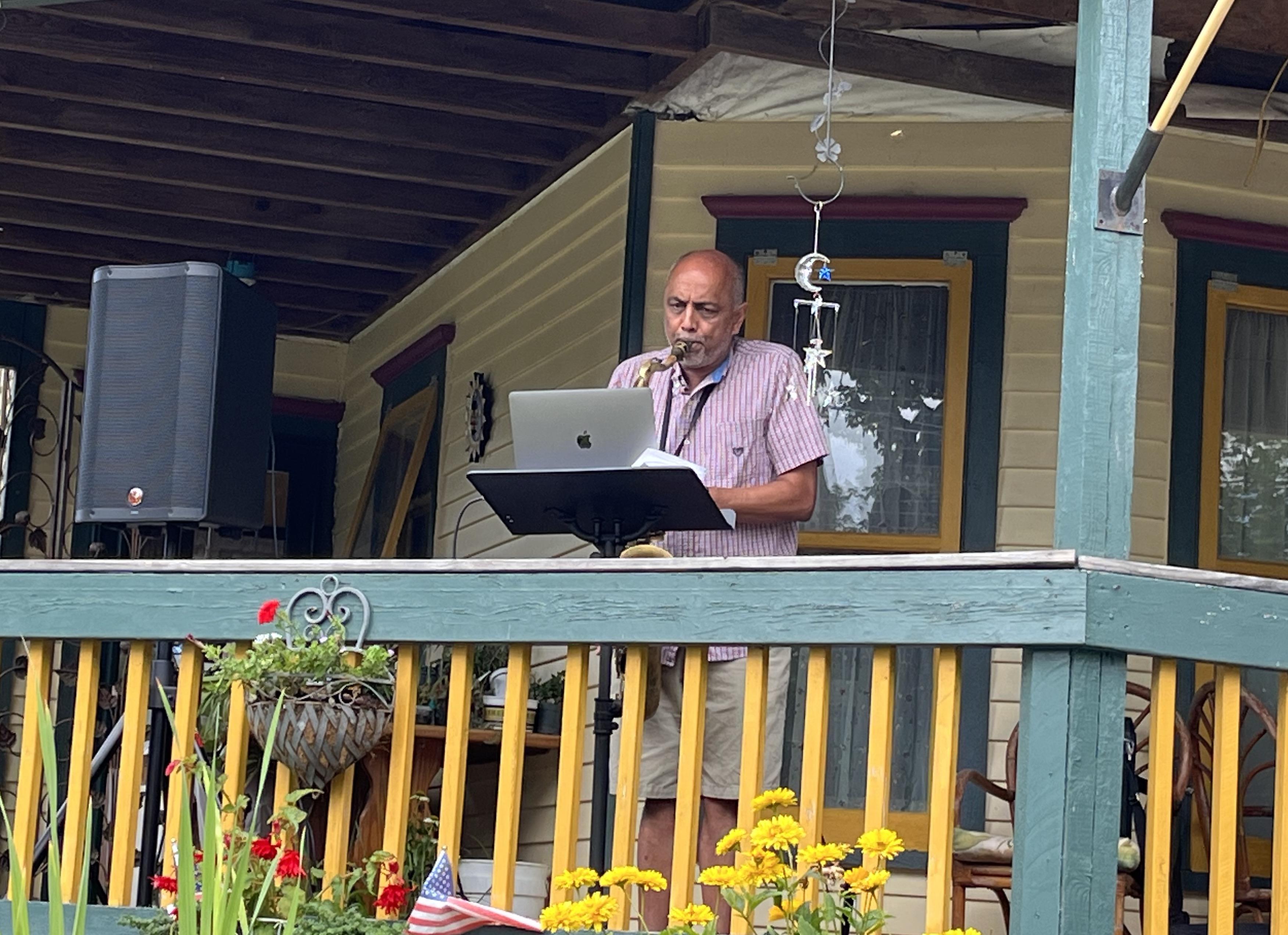 Shashi Kanbur plays the saxophone on a porch